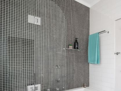 Contrasting black mosaic tiles cover the shower wall in this Marrickville bathroom