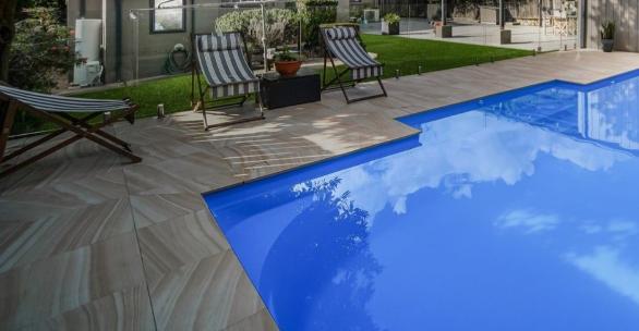 This pool in Bondi displays elegant, light beige tiles laid in a diagonal pattern around the water’s edge