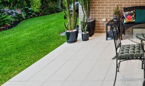 This patio in Manly features large, light-colored rectangular tiles arranged in a neat grid pattern