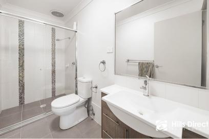 Rectangular grey floor tiles and vertical mosaic accents in the shower create a modern look similar to bathrooms in Epping